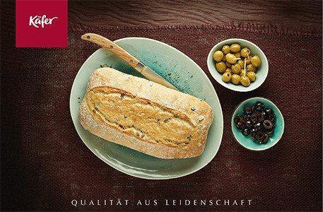 Brot auf Teller mit Oliven und Schalen daneben